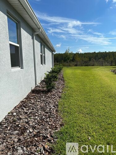 A house with a white wall and a green lawn in front.