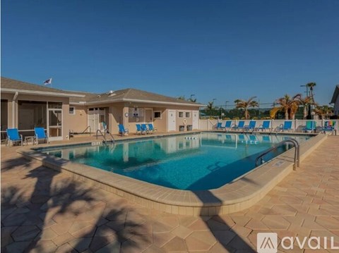 A swimming pool surrounded by a tiled patio and lounge chairs.