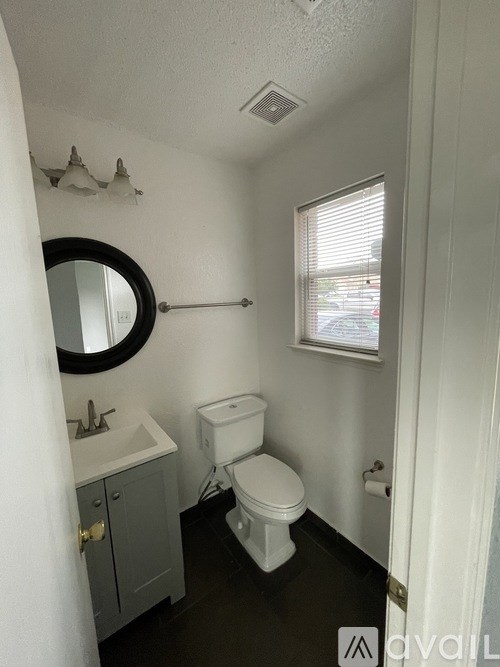 A white bathroom with a toilet, sink, and mirror.