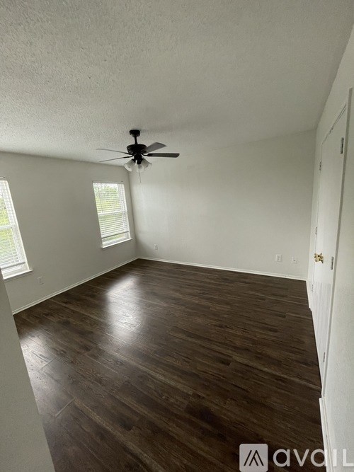 A room with a ceiling fan and wooden flooring.
