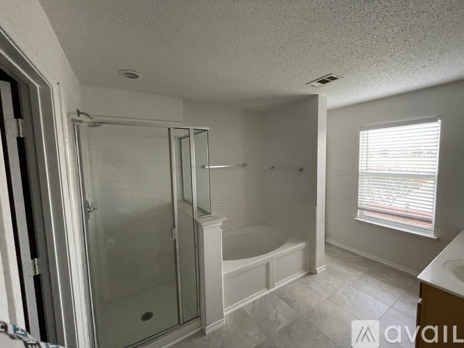 A bathroom with a glass shower door and a bathtub.