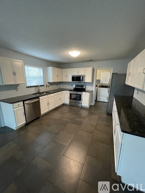 A kitchen with white cabinets and a black countertop.