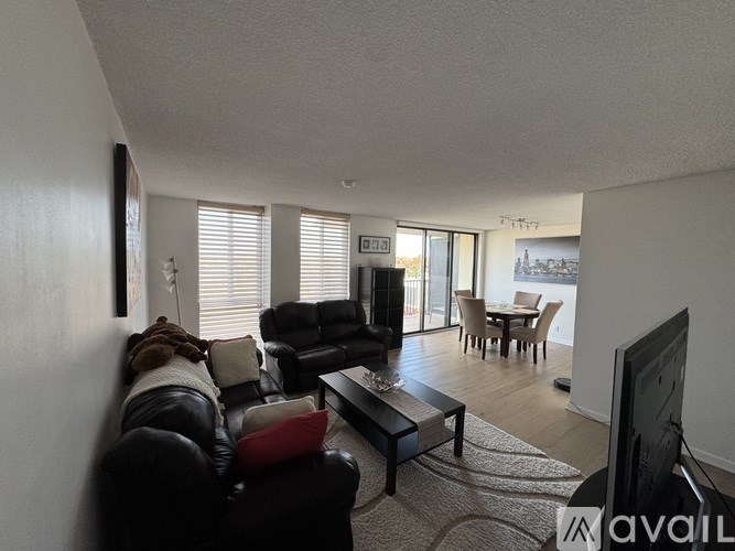 A living room with a black leather couch and a television.