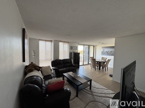 A living room with a black leather couch and a television.