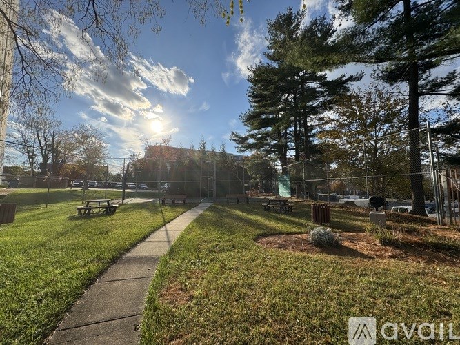 A park with a walking path, picnic tables, and trees.