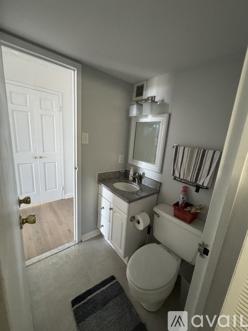 A bathroom with a toilet, sink, and mirror.