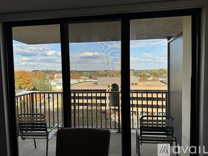 A balcony with two chairs and a table is overlooking a courtyard.