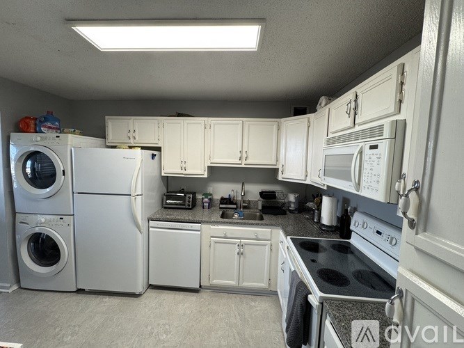 A kitchen with white appliances and cabinets.