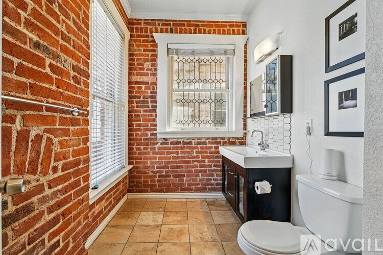 A bathroom with a brick wall and a white toilet.