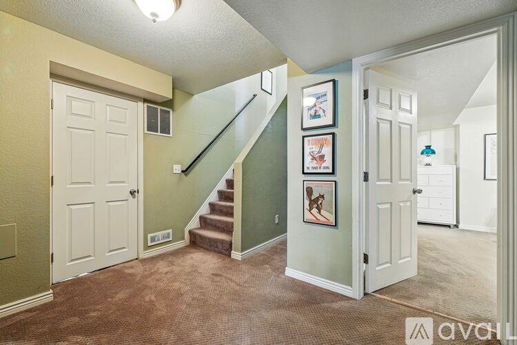 A hallway with a staircase and pictures on the wall.