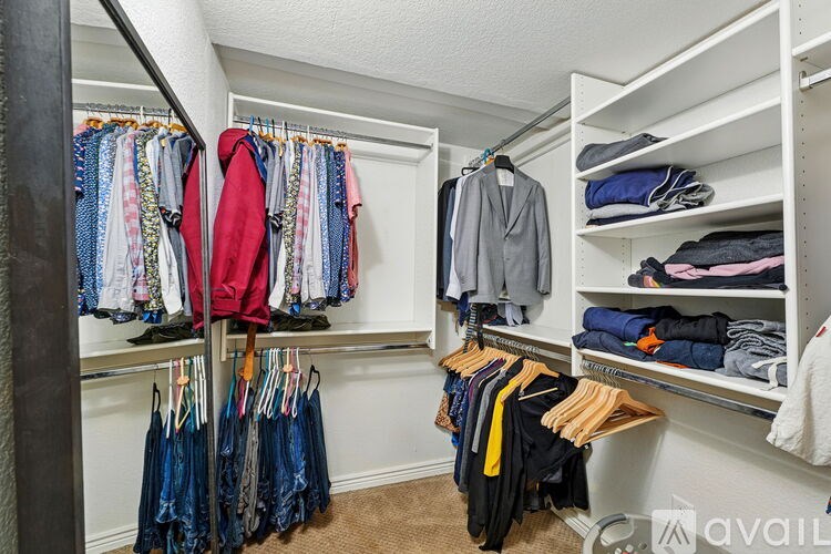 A white closet with clothes hanging and folded on shelves.