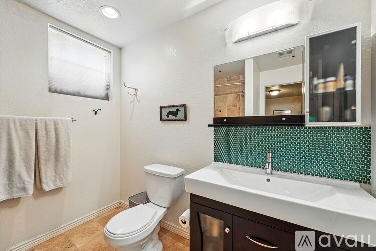 A bathroom with a toilet, sink, and mirror.