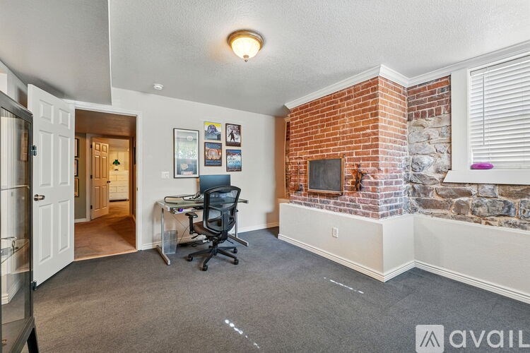 A room with a brick wall and a desk with a computer.