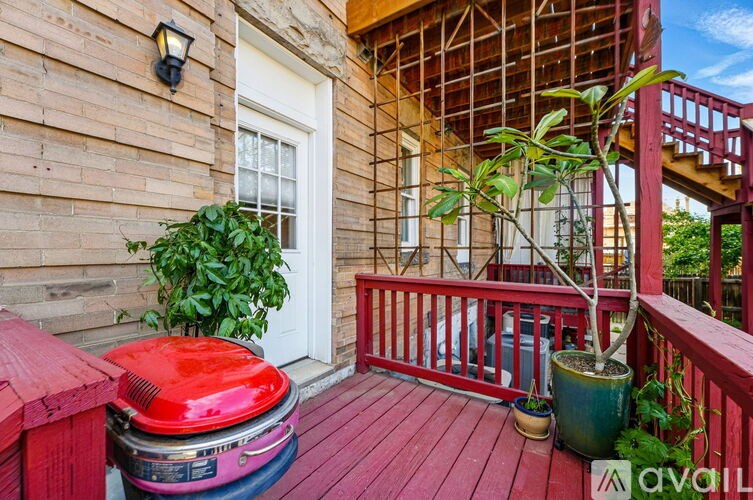 A red grill is on a wooden deck.