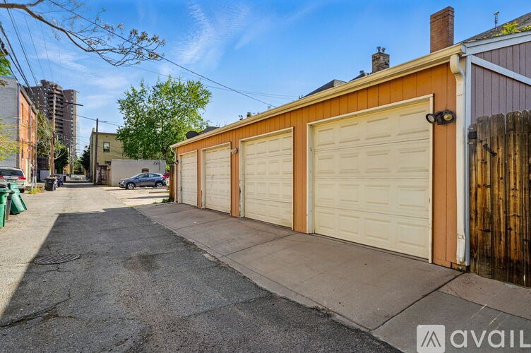 A row of garage doors are closed and the ground is wet.