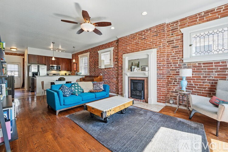 A living room with a blue couch and a brick wall.