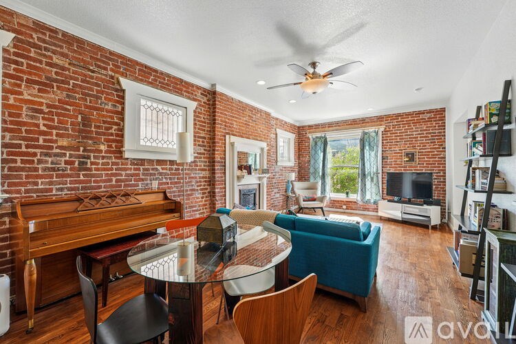 A living room with a brick wall and a piano.