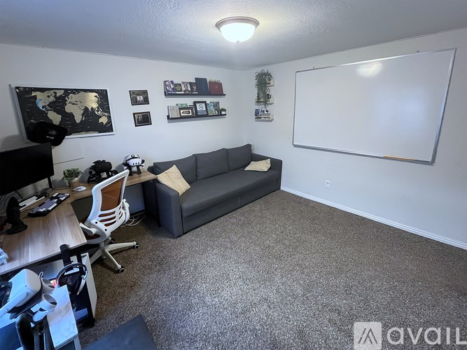 A room with a couch, chair, desk, and a world map on the wall.