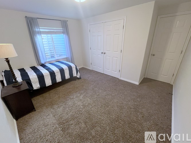 A bedroom with a bed, nightstand, and two doors.