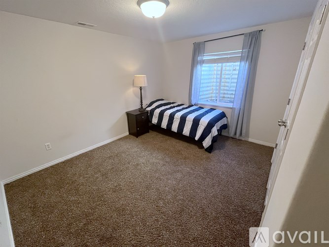 A bedroom with a bed, nightstand, and window.