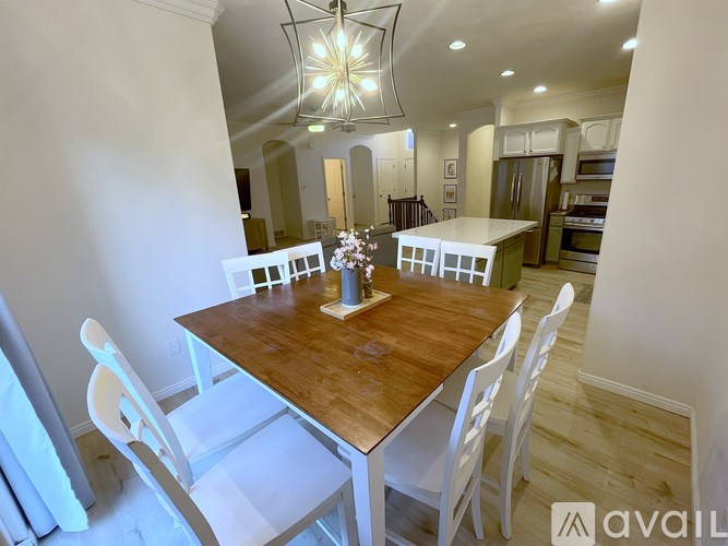 A dining room with a wooden table and white chairs.