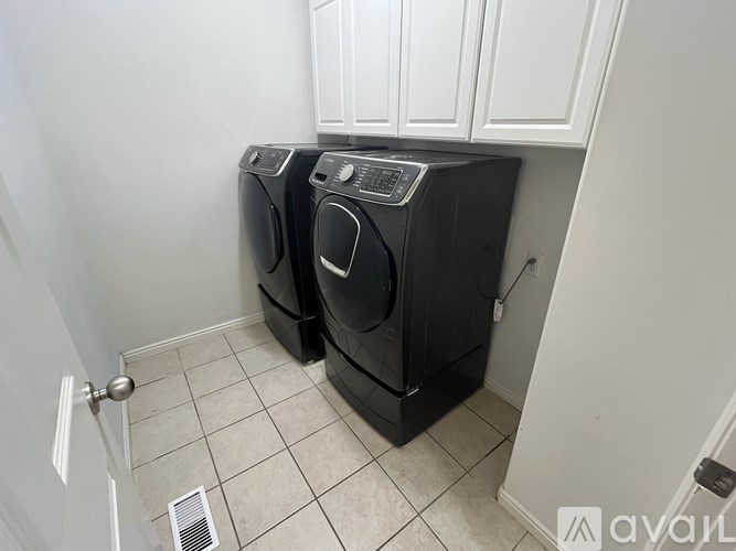 Two black front load washing machines in a small laundry room.