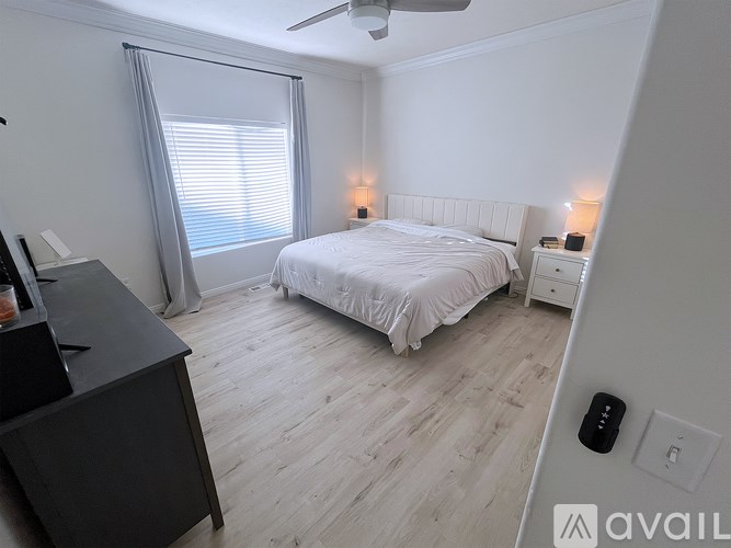 A bedroom with a bed, nightstand, and a desk with a computer.