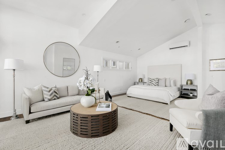 A modern living room with a white couch, a round mirror, and a coffee table.