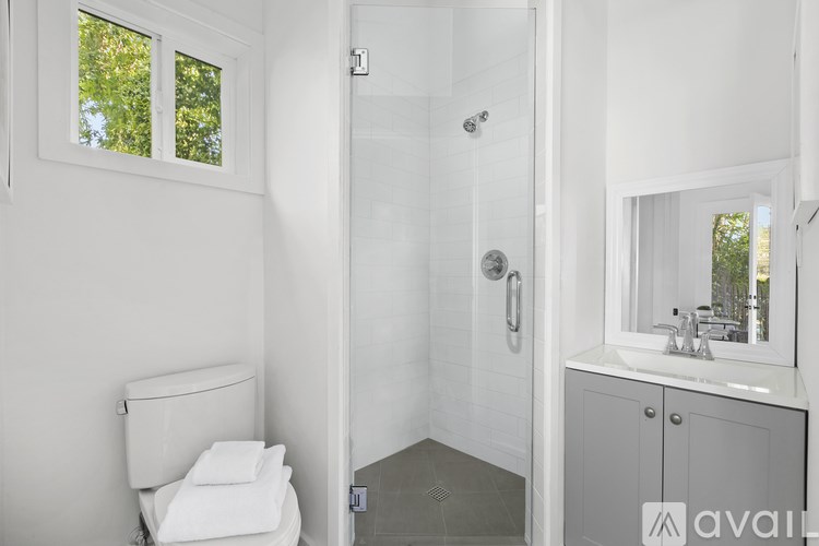 A white bathroom with a toilet, sink, and shower.