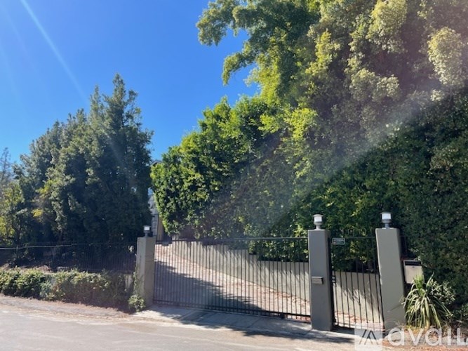 A black metal gate with two posts and a small sign on top is closed.