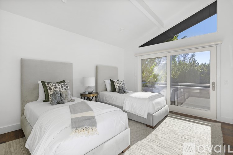 Two white beds with pillows and blankets in a room with a sliding glass door.