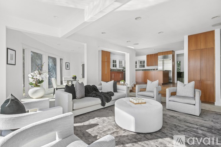 A modern living room with white furniture and a grey rug.