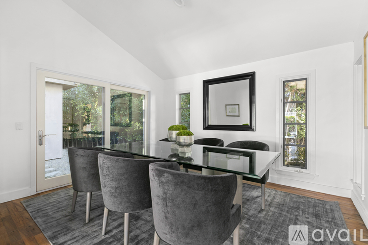 A dining room with a glass table and grey chairs.