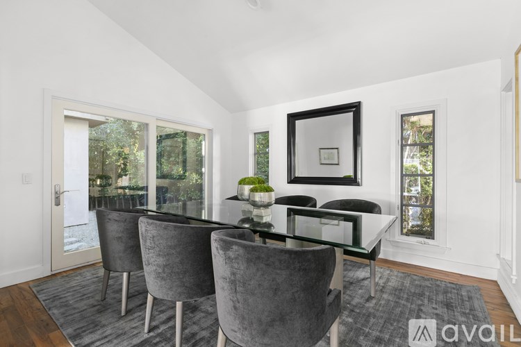 A dining room with a glass table and grey chairs.