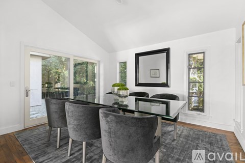 A dining room with a glass table and grey chairs.