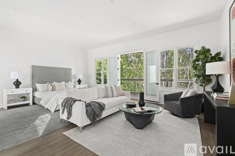 A modern bedroom with a large bed and a grey sofa.