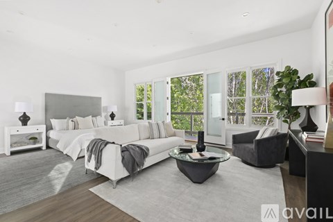 A modern bedroom with a large bed and a grey sofa.