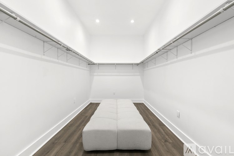 A long white couch sits in a white room with wooden floors and white walls.