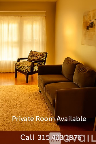 A living room with a couch, chair and a window with curtains.