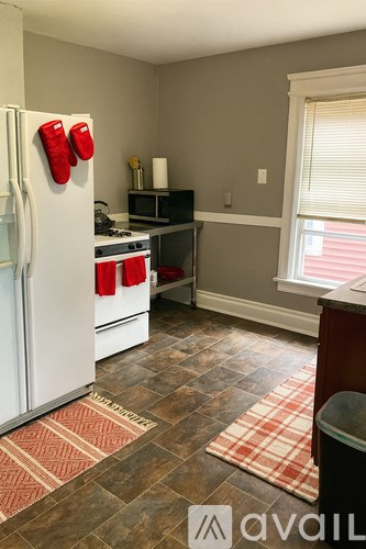 A kitchen with a white fridge and red oven mitts hanging on it.