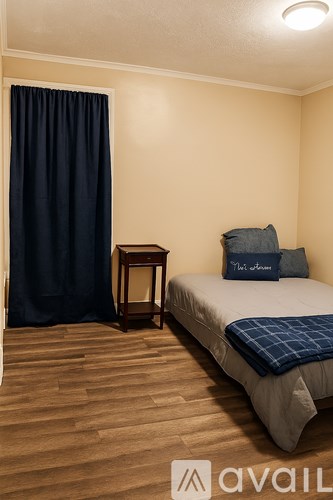 A bedroom with a bed, a nightstand, and a chair.