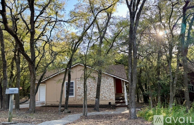 A house is surrounded by trees and has a mailbox in front.