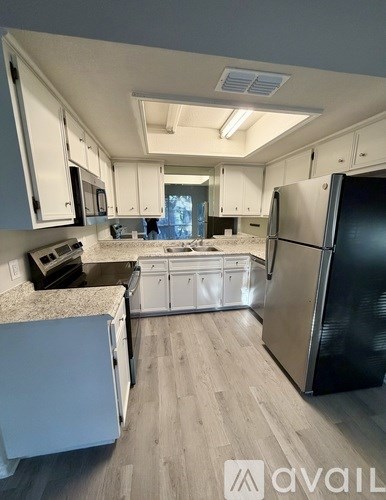 A kitchen with a black refrigerator and white cabinets.
