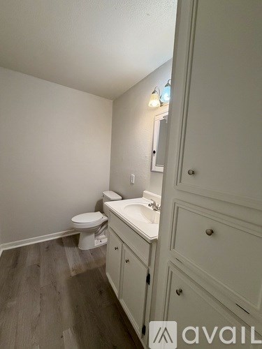 A bathroom with a toilet, sink, and cabinet.