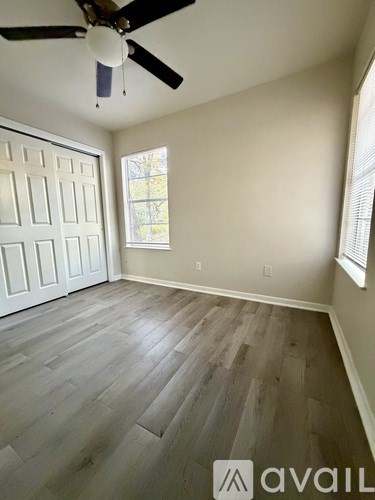 A room with a ceiling fan and wood flooring.