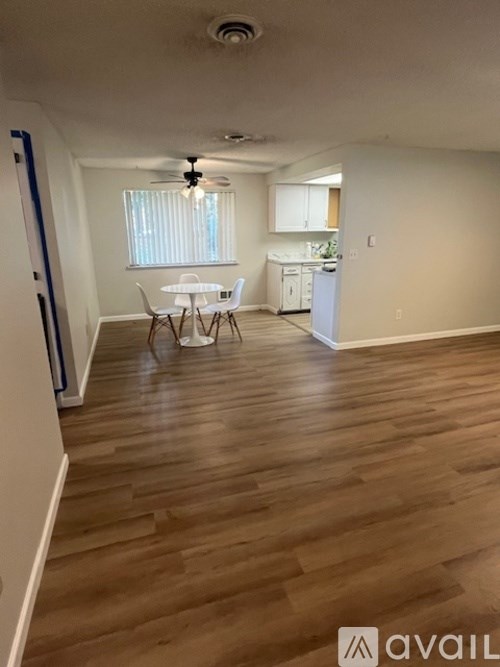 A room with wooden flooring and a dining table set up.