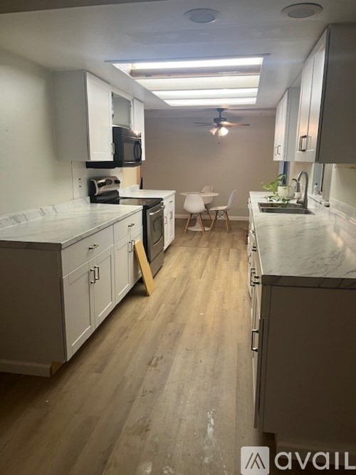 A kitchen with white cabinets and a wooden floor.