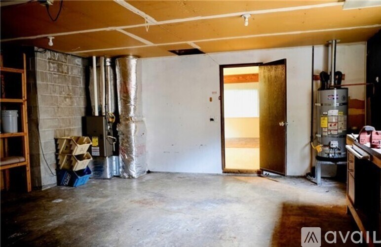 A room with a ladder, a door, and a wall with pipes.