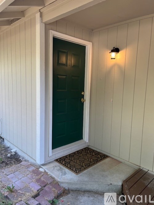 A green door is at the end of a white-sided hallway.
