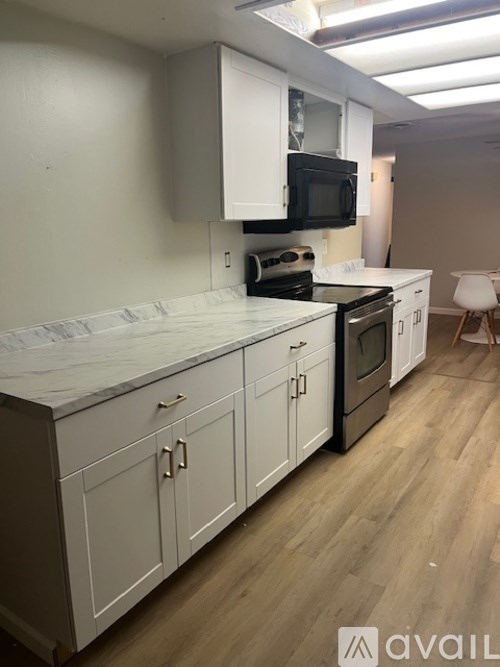 A kitchen with white cabinets and a black microwave.